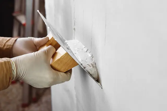 Stuckateur trägt Innenputz mit der Glättkelle auf